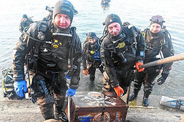Marcus Voigt (links) und Jörg Posen vom Tauchsport-Club Kressbronn tragen die Schatzkiste aus dem See. Im Hintergrund rechts Adrian ...