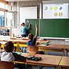 Schulkinder einer fünften Klasse des Kreisgymnasiums in Bad Krozingen sitzen an ihren Tischen, während eine Referendarin an der Tafel ...