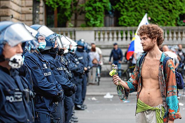 Ein Demonstrant hält vor der russischen Botschaft Blumen vor Polizisten.