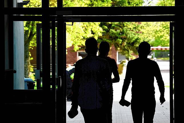 Drei Asylbewerber laufen aus einem Gebäude der Landeserstaufnahmeeinrichtung Sigmaringen hinaus.