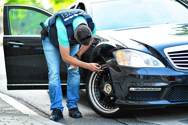 Ein Polizist kontrolliert die Felge eines Autos. Im Kampf gegen Auto-Poser, Fahrzeughalter die mit illegalen Auspuffanlagen und ...