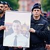 Polizisten tragen bei einem Trauermarsch für den bei einer Messerattacke tödlich verletzten Polizisten Rouven Laur dessen Bild.