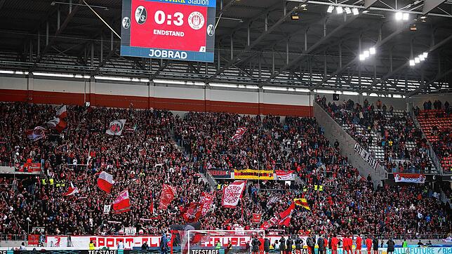 Die Spieler des SC Freiburg stehen vor ihrer Fankurve während darüber die Anzeigetafel mit dem Endstand von 0:3 zu sehen ist.