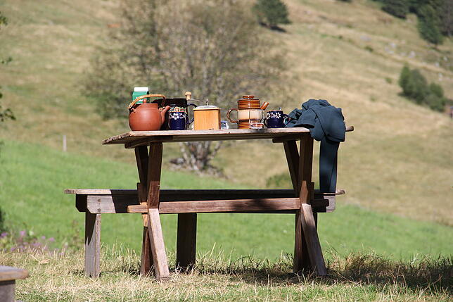 Damals wie heute wird dieser Holztisch im Freien genutzt zum Kaffeetrinken.