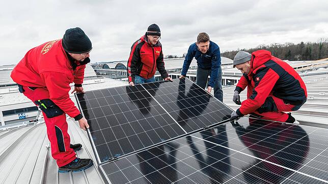 Auf einem Messedach werden PV-Module montiert.