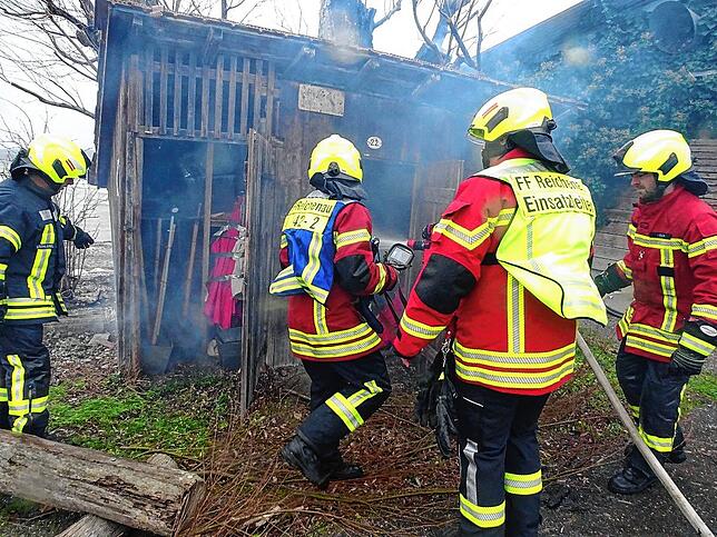 Einsatzkräfte der Feuerwehr versuchen das Übergreifen der Flammen auf einen dem Baum benachbarten Schuppen zu verhindern.