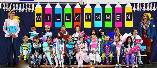 Klassenlehrerin Julia Büchler heißt ihre neuen Erstklässler, die mit kunterbunten Schultüten ausgerüstet sind, herzlich willkommen.