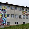 Das Banner für die Schulhaus-Fassade sowie die Köpfe am Fenster haben die Schülerinnen und Schüler der Goldösch-Schule gestaltet.