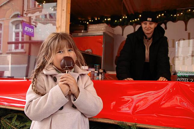 Aliya beißt in einen Schoko-Apfel, den es am Stand von Angeliki Müller am Familientag für 2,50 Euro statt 3,50 Euro gibt.
