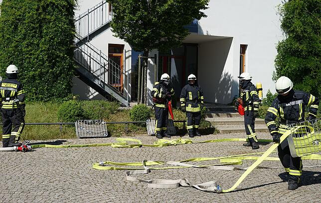 Während ein Teil der Feuerwehrleute die Schläuche auslegt, haben andere bereits ihre Atemschutzgeräte angelegt.