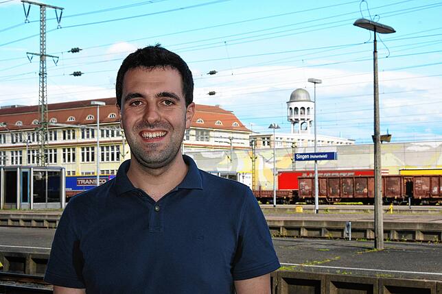 Simon Götz vor dem Bahnhof von Singen. Im Hintergrund das markante Maggi-Werk mit dem denkmalgeschützten Wasserturm.