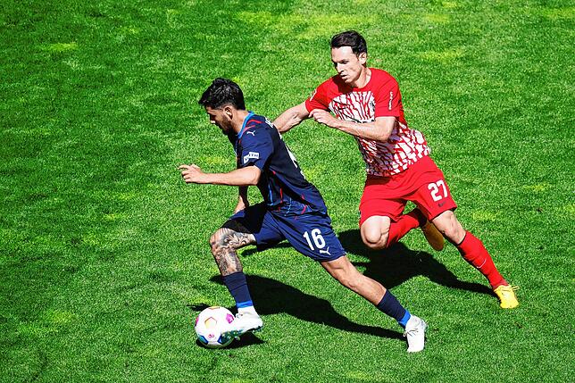 Heidenheims Kevin Sessa (l) im Duell mit Freiburgs Nicolas Höfler (r).