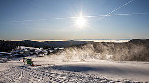 Eine Schneekanone beschneit eine Piste zwischen dem Feldbergturm und der Talstation der Feldbergbahn.