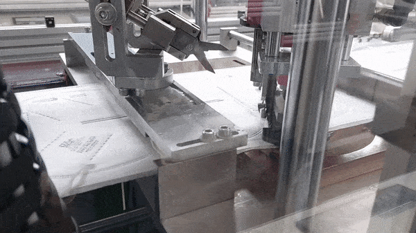 Eine Schere schneidet die Gummibänder zurecht, die die Maschine auf die Masken schweißt.
