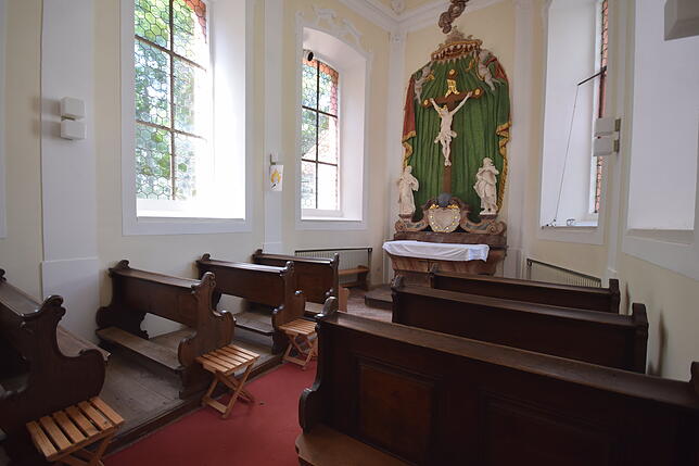 Die Schlosskapelle bietet kleine Sitzbänke und hat hohe Fenster. Sie ist noch geweiht und heiraten wäre hier möglich.