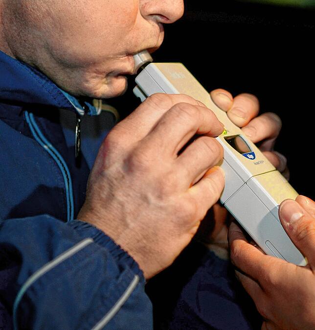 Ein Beamter führt während einer Polizeikontrolle bei einem Mann einen Alkoholtest durch (Archivbild).