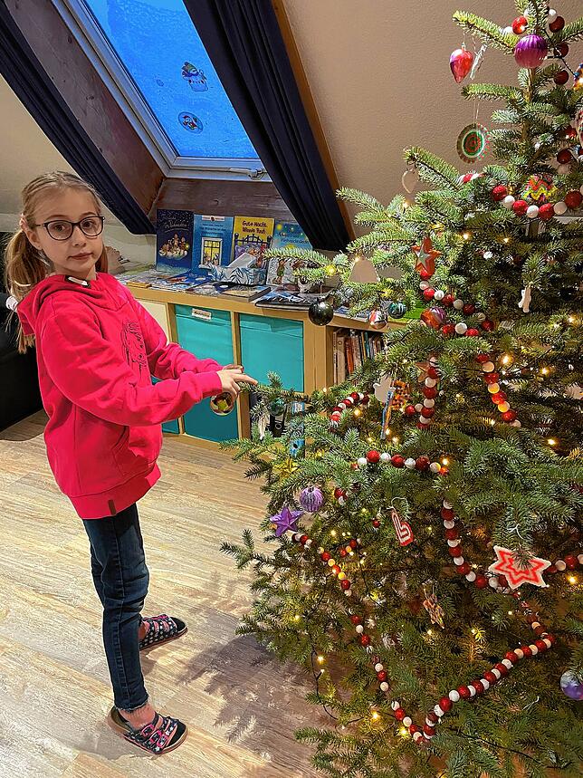 Elena hängt den von den Kindern selbstgebastelten Baumschmuck auf.