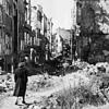 Eine Frau geht in einer Straße in Dresden an Häusern vorbei, von denen nach dem Zweiten Weltkrieg nur noch Ruinen geblieben sind. Viele ...