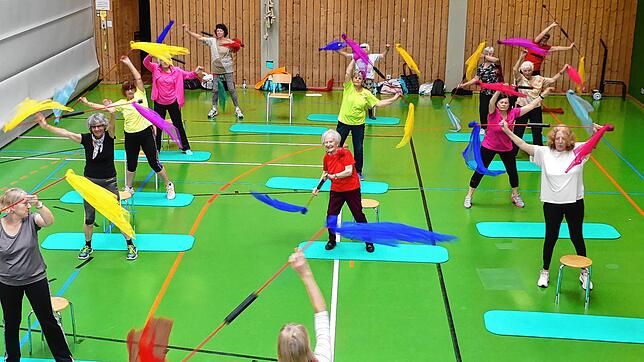 Eines von vielen Fitnessangeboten. Die Riegenleiterin Conny Gagliardi im Vordergrund macht die Übung mit Schwingstäben und Tüchern vor. ...