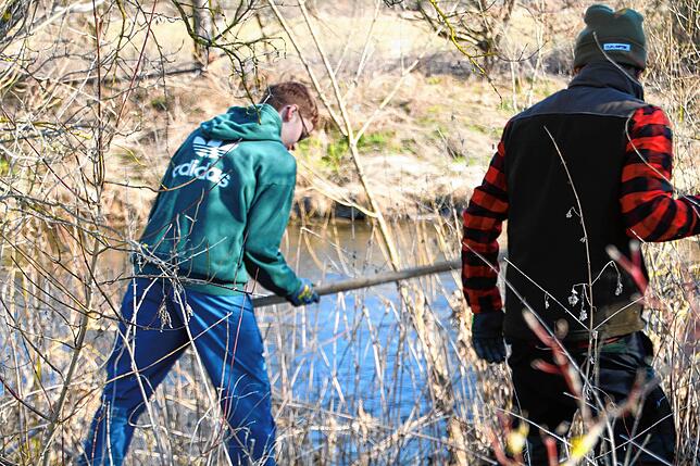 Unter der Aufsicht der Mitglieder der Anglervereinigung hacken die Schüler Löcher in die Erde.