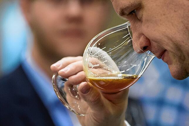 Ein Mann riecht während der Fachmesse an einem Glas Craft Beer – Bier, das von unabhängigen Brauern in kleineren Mengen gebraut wird.