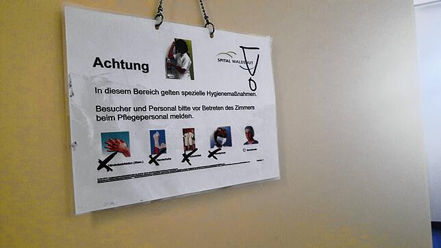 Ein Hinweisschild wird an der Tür angebracht, wenn das Isolierzimmer belegt ist.