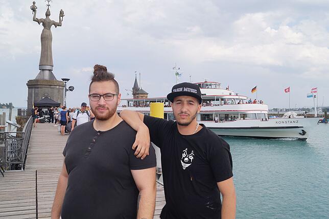 Yasin (rechts) und Lupo vor der Imperia und dem Passgierschiff Konstanz im Hafen.