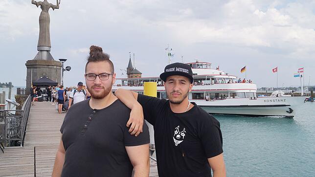 Yasin (rechts) und Lupo vor der Imperia und dem Passgierschiff Konstanz im Hafen.