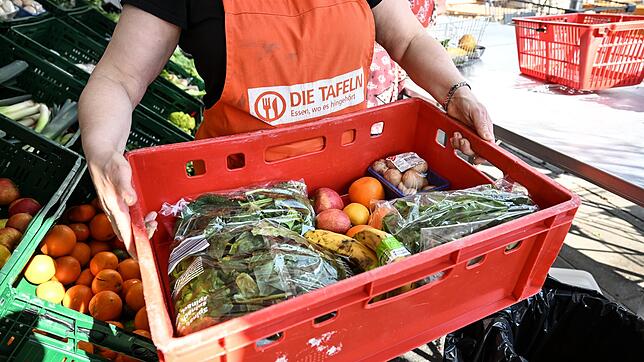Eine Mitarbeiterin des Tafel-Ladens in Singen trägt eine Kiste voll mit Obst und Gemüse. Für Menschen in Not sind die Tafeln in ...