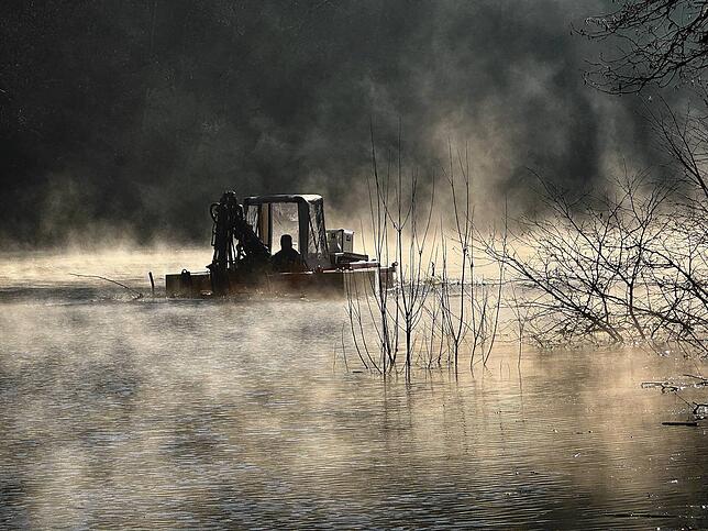Idylle im Nebel: Mit einem Amphibienfahrzeug wird das Wehrabecken von Laub, Ästen und Baumstämmen befreit.
