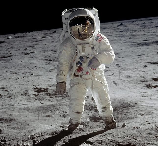 Edwin Aldrin steht auf der Mondoberfläche. Im goldbedampften Glas seines Helms spiegelt sich Neil Armstrong.
