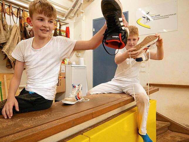 Jan (10 Jahre) und Tim (11 Jahre) leeren das Sägemehl nach dem Training aus ihren Schuhen.