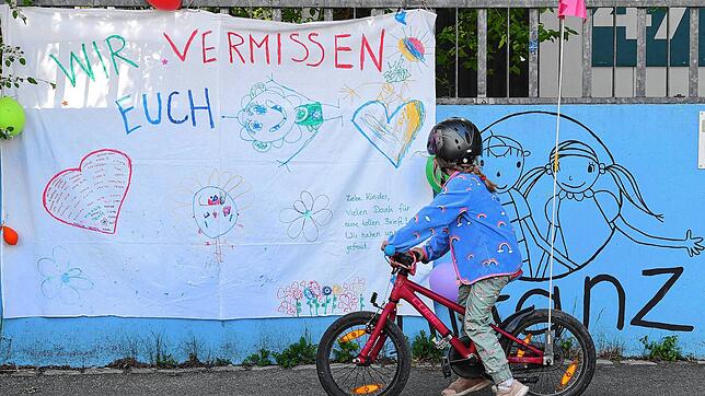 Ein Kindergartenkind steht vor seinem geschlossenen Kindergarten in Stuttgart.