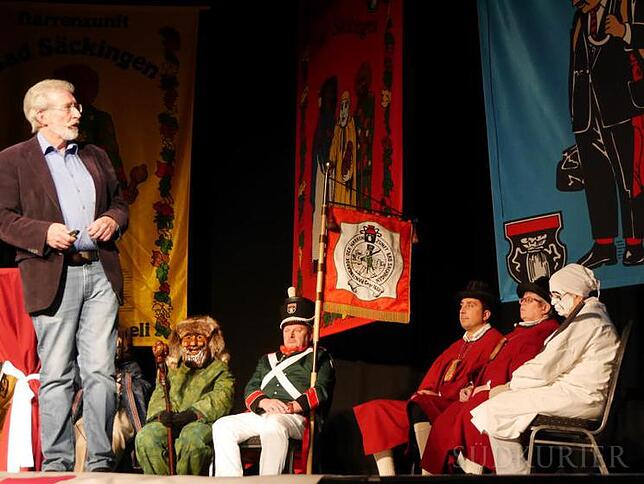 Dozent der Kinderuni Werner Mezger (li.), umringt von Mitgliedern der Narrenzunft (Maisenhardt-Joggele, Ranzengarde, Zunfträte und ...