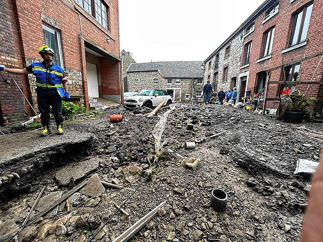 Hochwasser-Alarm auch in Belgien: In Lüttich steht ein Feuerwehrmann an einer durch die Überschwemmungen aufgerissenen Straße