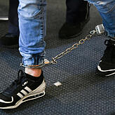 Ein Angeklagter kommt mit Fußfesseln in den Saal des Freiburger Landgerichts. Die elf Angeklagten sollen 2018 eine 18-Jährige vor einer ...