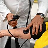 Ein Arzt kontrolliert den Blutdruck eines Patienten.