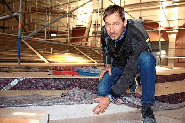 Architekt Gerhard Lallinger zeigt die neu eingebauten Altarstufen aus Jura Grau, die zum Schutz in Holz und Malervlies verpackt sind.