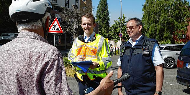 Polizist Niklas Burchard (links) und Andreas Bohn vom Gemeindevollzugsdienst (rechts) weisen die Fahrradfahrer auf ihr Fehlverhalten hin.