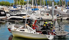 Die Radolfzeller Feuerwehr schleppt das gekenterte Segelboot an und bringt es zurück in den Hafen.