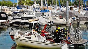 Die Radolfzeller Feuerwehr schleppt das gekenterte Segelboot an und bringt es zurück in den Hafen.