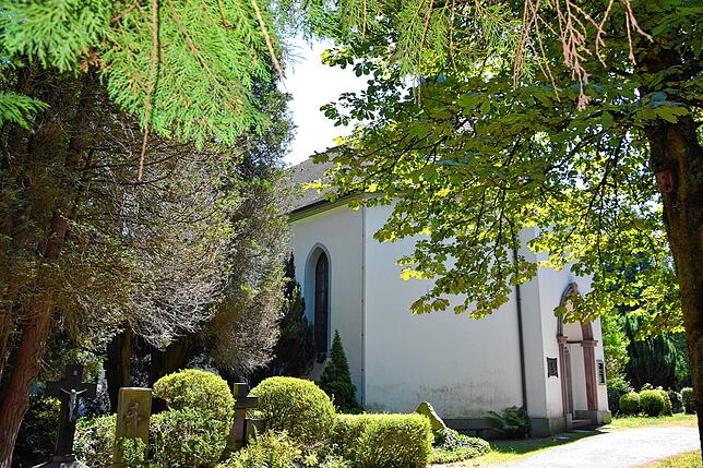 Zwischen hohen Bäumen und alten Grabstätten liegt die Kirche St. Peter und Paul der alt-katholischen Kirchengemeinde Hochrhein-Wiesental ...