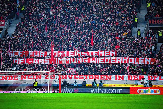 Die Fans des SC Freiburg halten ein Plakat mit der Aufschrift ·SCF: Für 50+1 Einstehen DFL – Abstimmung wiederholen· hoch.