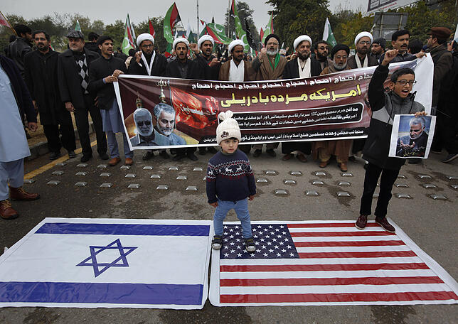 Schiitische muslimische Kinder stehen auf einer amerikanische Flagge, die neben einer israelischen auf dem Boden liegt. Pakistanische ...