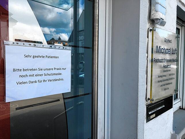 Ein Schild am Praxiseingang weist auf die Mundschutzpflicht hin.
