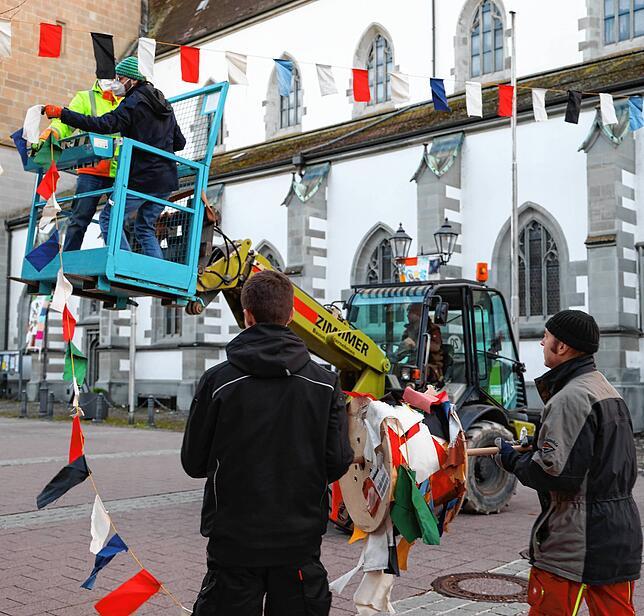 Aufhängen der Bändel auf dem Marktplatz: Während im Hintergrund Christoph Joos und Tobi Hinckeldein in luftiger Höhe die Bändel ...