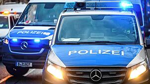 Polizeiautos mit eingeschalteten Scheinwerfern und Blaulicht. (Symbolbild)