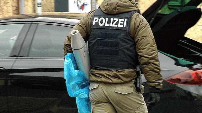Ein Polizist trägt vor der Gaststätte „Bull‘s Eye“ einen Gegenstand zu einem Auto.
