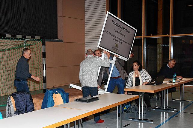 Der Ortschaftsrat stellt in der Sporthalle den Bildschirm auf ein Podest, damit er von den zahlreichen Zuhörern besser eingesehen werden ...