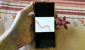 Eine Person beobachtet den Kurs einer Krypto-Währung auf dem Smartphone (Symbolbild).